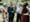 A group of well-dressed people are standing in the garden holding a flute and chatting